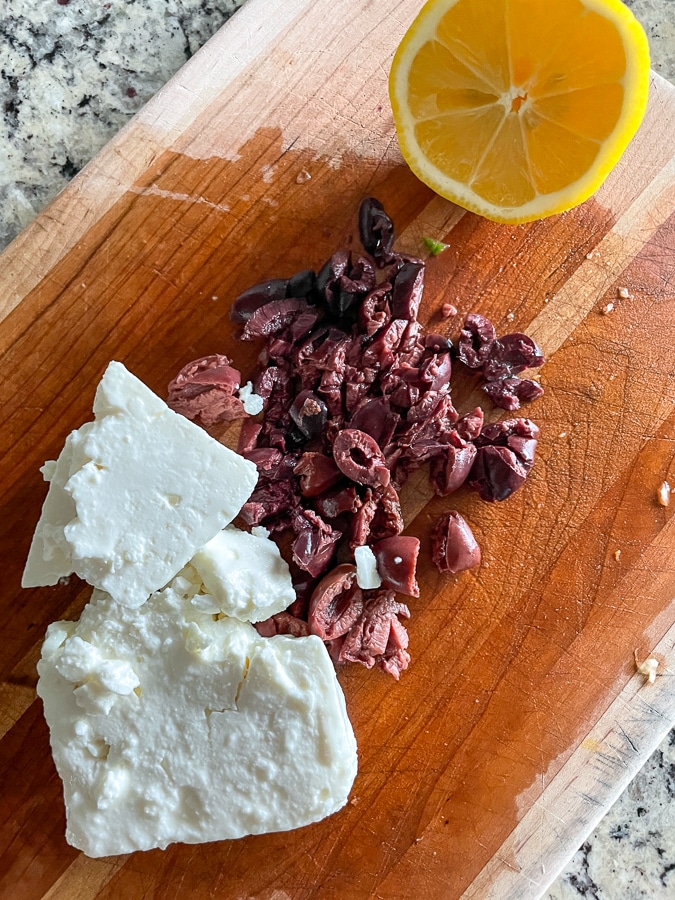 Aceitunas, queso feta y limón en una tabla para cortar