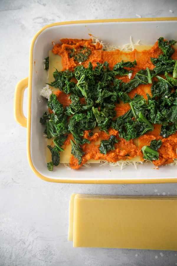 kale and pumpkin in a casserole dish with no boil noodles on the side