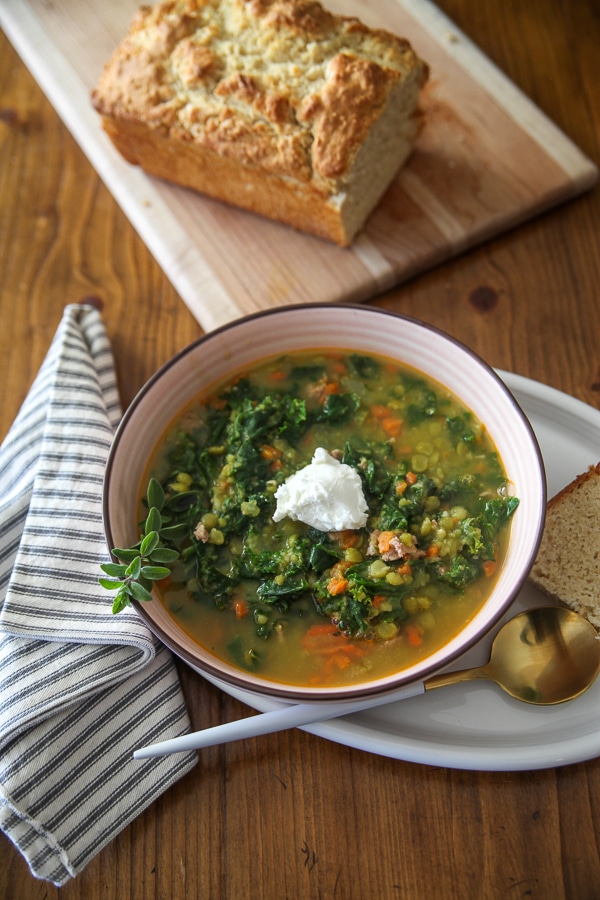 pea and sausage soup with a striped napkin and bread on a cutting board