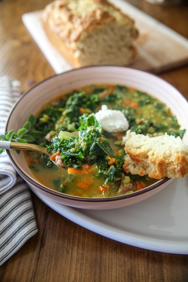 kale and pea soup on a spoon with crusty bread