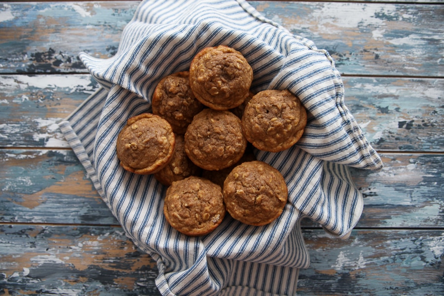 whole wheat muffins in a basket on a blue wooden board