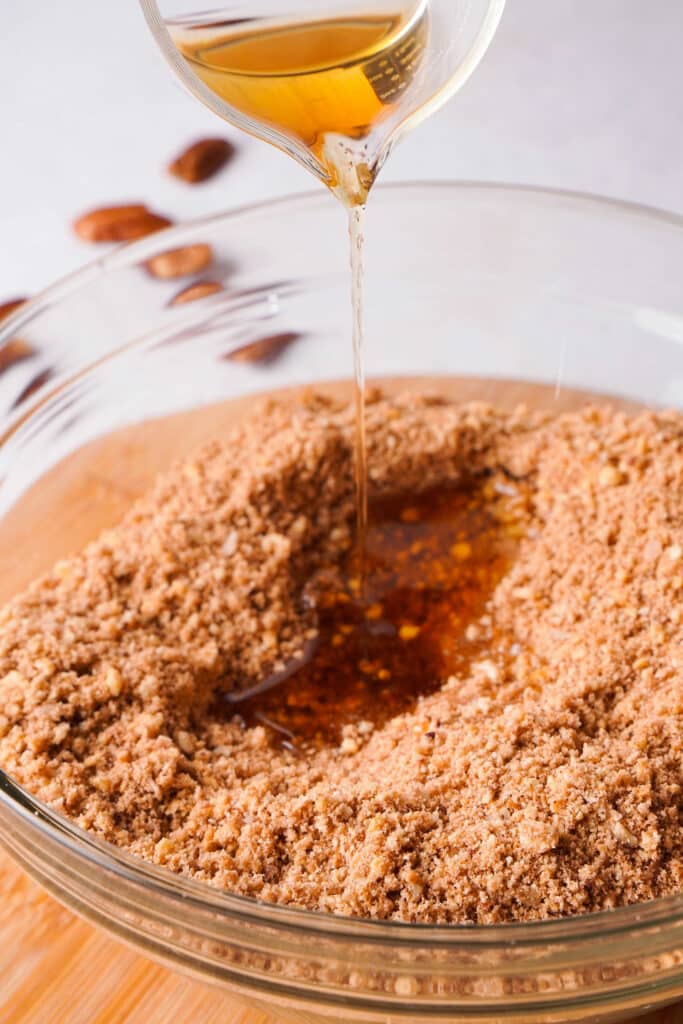 pouring honey and bourbon on cookie crumbs