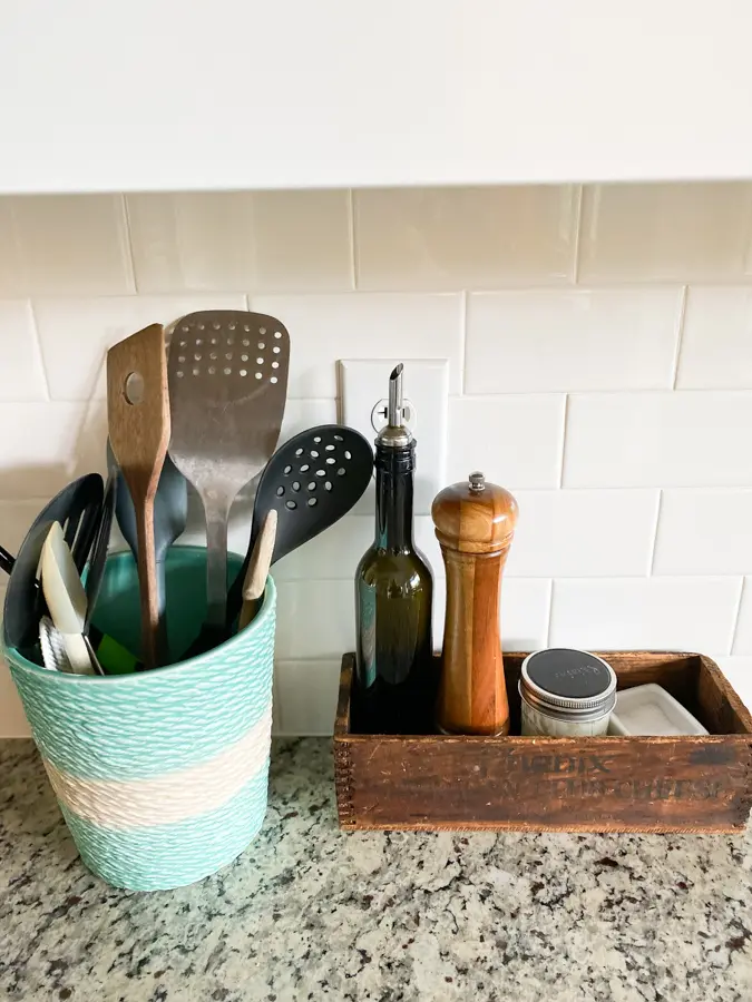 organized kitchen utensils in an aqua beachy holder and condiments in a wooden vintage box