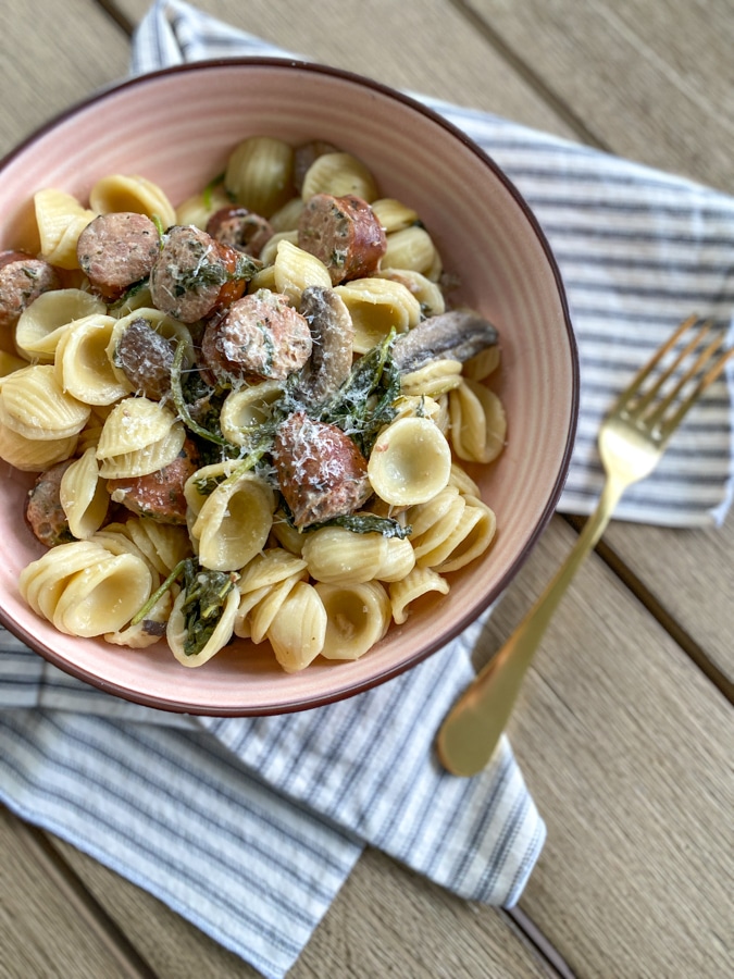 Orecchiette with Sausage and Mushrooms in a pink bowl and gold fork