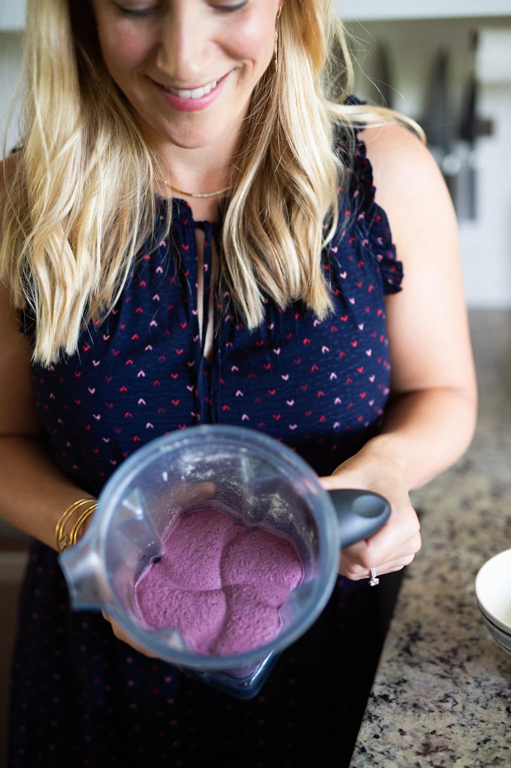 Kath Younger holding Vitamix blender with thick, purple berry smoothie.