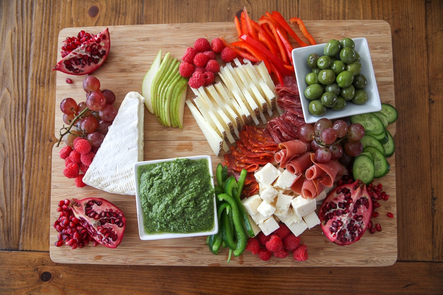 half finished charcuterie board with fruits and veggies filled in