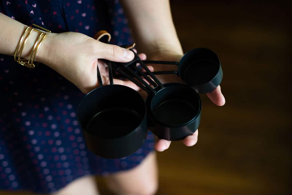 Hand holding set of black measuring cups.