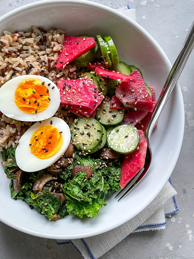 soft boiled egg with sesame seeds, cucumber, and radish