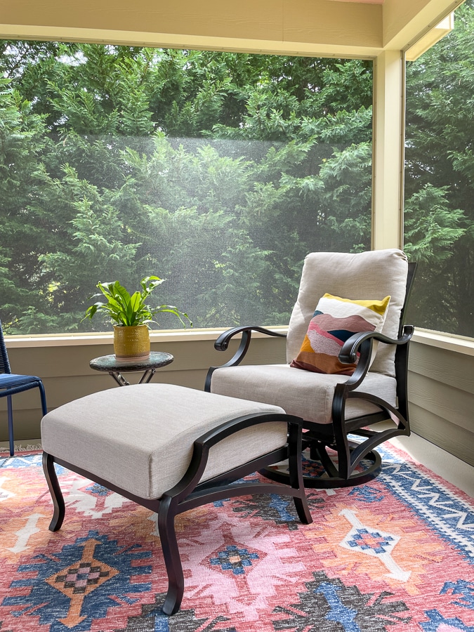 swivel rocker with west elm pillow and rug on screened in porch