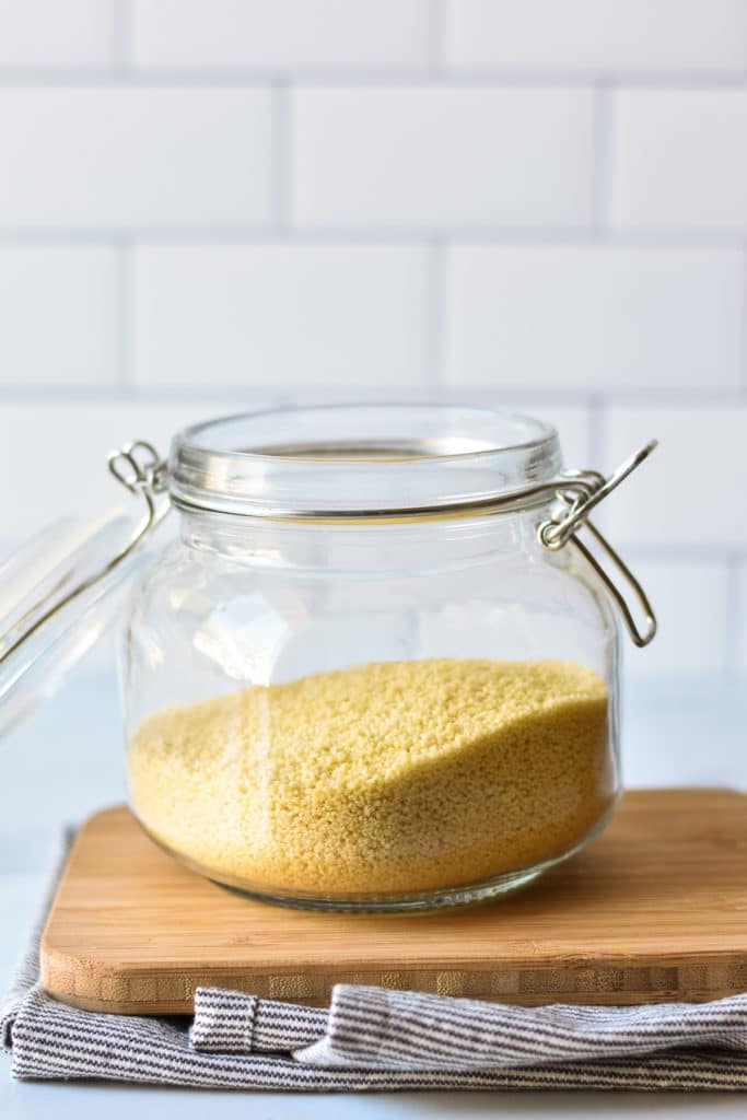 jar of couscous on wooden cutting board