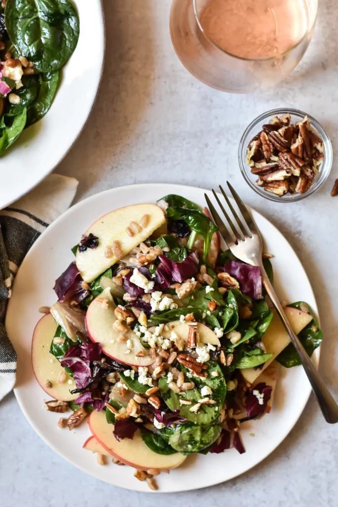 radicchio and wheatberry salad on a plate with dish of pecans and a glass of wine