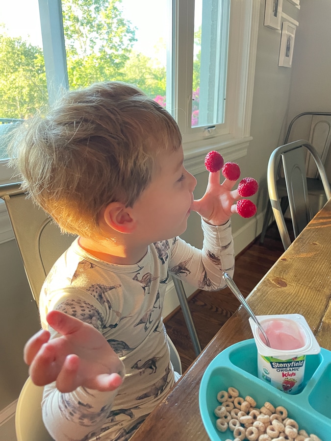 Child with raspberries on fingers