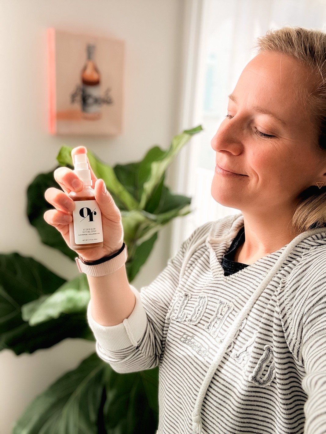 Kath Younger holding Olive Rose HT Skin glow setting spray with a fig in the background