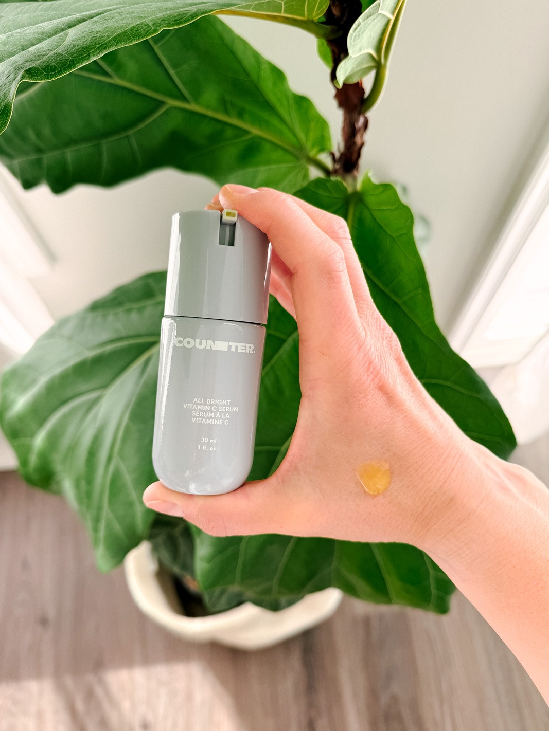 Counter All Bright C Serum in a hand with a fig in the background