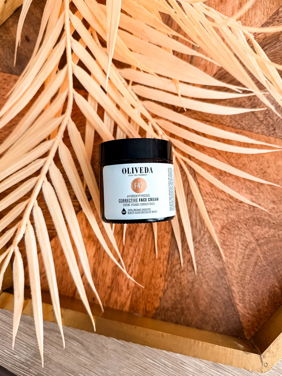 Oliveda F42 Corrective Face Cream on top of a palm leaf